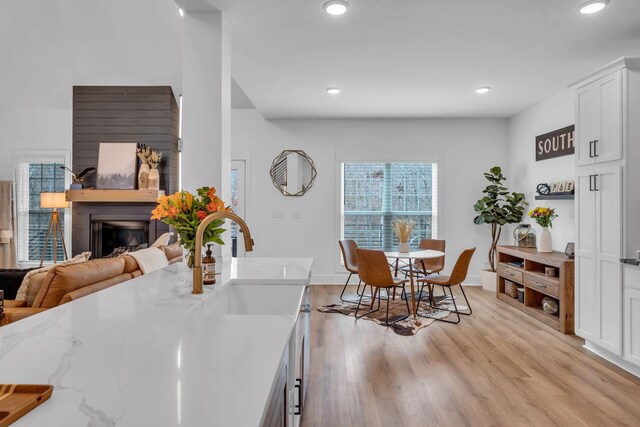 dining area featuring baseboards, light wood-type flooring, a fireplace, and recessed lighting