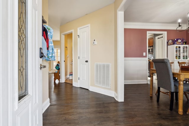 interior space featuring dark wood-style floors, visible vents, crown molding, and baseboards