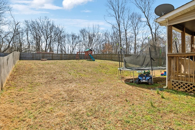 view of yard featuring a trampoline, a playground, and a fenced backyard