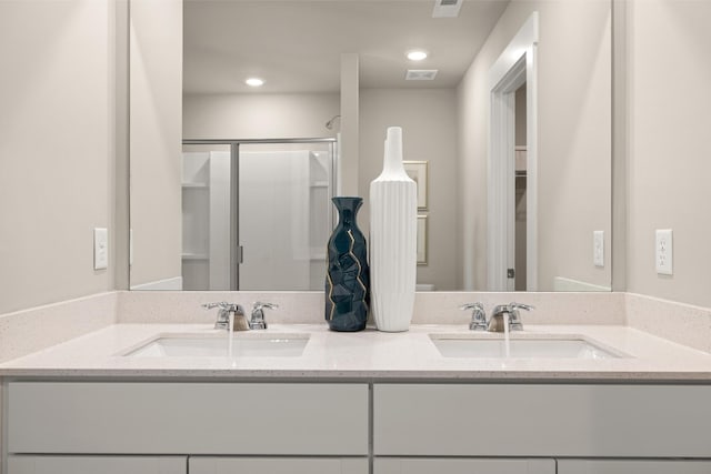 full bath with double vanity, a shower stall, a sink, and recessed lighting