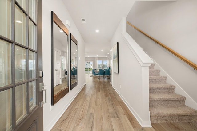 corridor with light wood finished floors, recessed lighting, visible vents, baseboards, and stairs