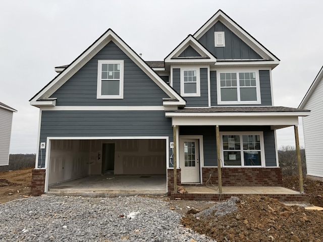 craftsman-style house with covered porch, a garage, brick siding, driveway, and board and batten siding