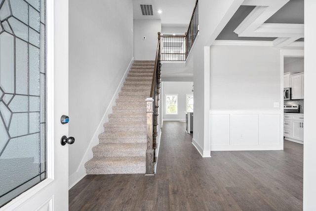 foyer entrance with visible vents, dark wood finished floors, stairway, ornamental molding, and a high ceiling