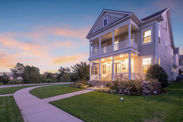 view of front of house featuring covered porch, a yard, and a balcony