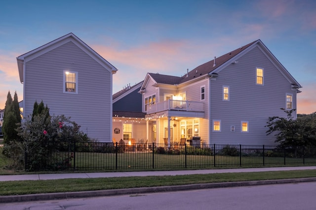 exterior space with a balcony, a fenced front yard, and a yard