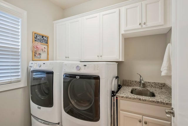 washroom featuring cabinet space, washing machine and dryer, and a sink