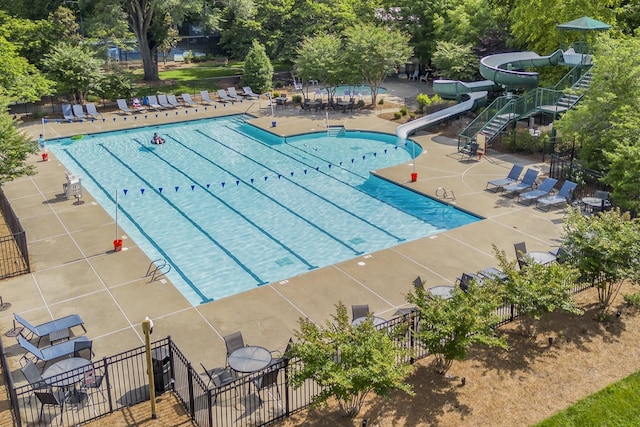 pool with a water slide, fence, and a patio