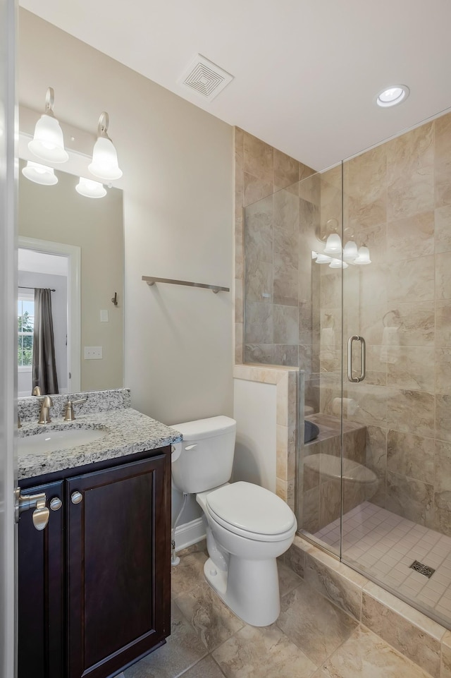 bathroom with visible vents, toilet, a shower stall, vanity, and baseboards