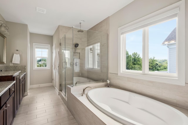 full bathroom with a stall shower, visible vents, baseboards, a garden tub, and vanity