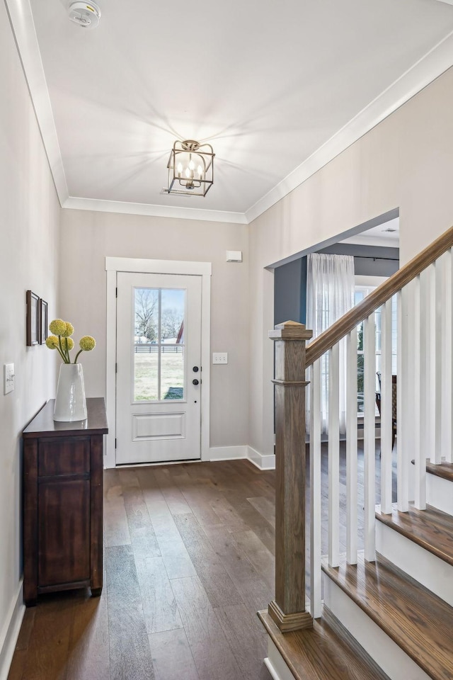 entryway featuring baseboards, ornamental molding, wood finished floors, stairs, and a notable chandelier