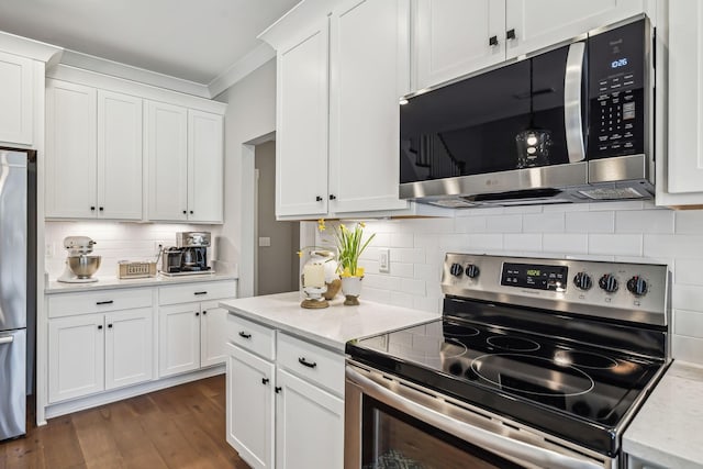 kitchen featuring decorative backsplash, dark wood finished floors, ornamental molding, stainless steel appliances, and white cabinetry