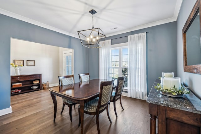 dining area with a notable chandelier, wood finished floors, visible vents, baseboards, and crown molding