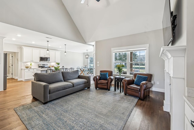 living area with a ceiling fan, light wood-style flooring, high vaulted ceiling, and baseboards