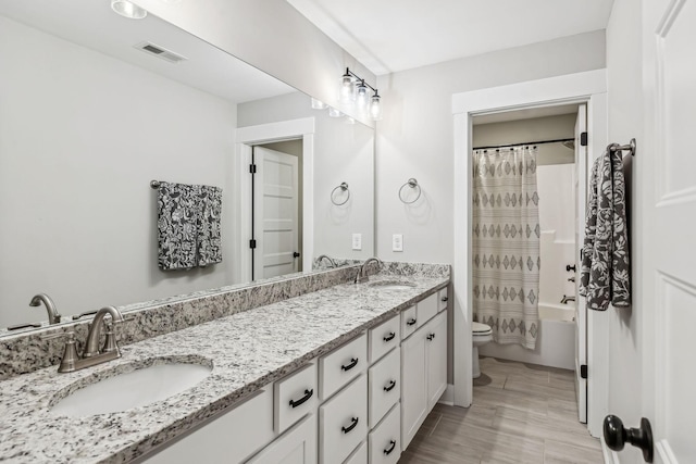 full bathroom featuring toilet, double vanity, a sink, and visible vents