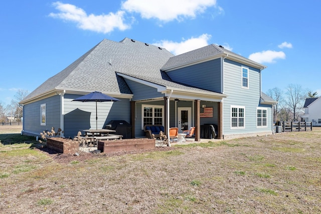 back of house featuring a shingled roof, a yard, and a patio