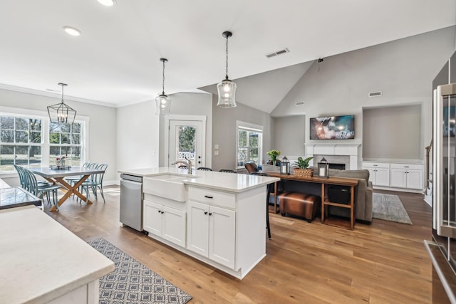 kitchen featuring a fireplace, visible vents, white cabinets, a sink, and dishwasher