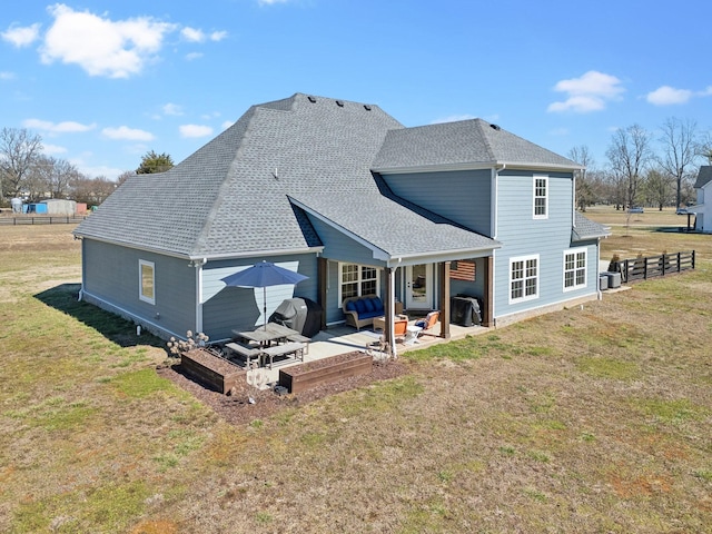 rear view of house with a yard, a patio, and a shingled roof