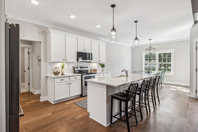 kitchen featuring stainless steel appliances, light countertops, backsplash, dark wood-type flooring, and a sink