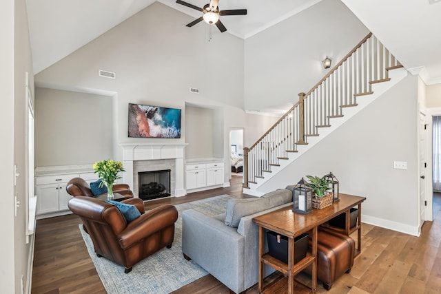 living area featuring stairway, a fireplace, visible vents, and wood finished floors