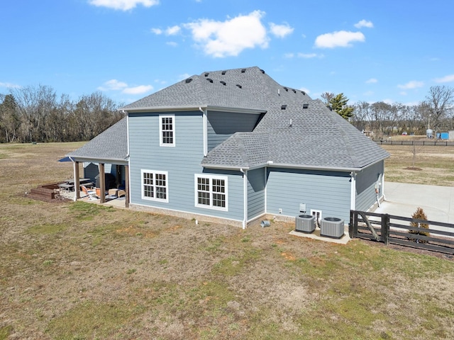 rear view of property with a yard, a shingled roof, fence, and central air condition unit