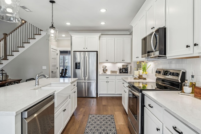 kitchen featuring appliances with stainless steel finishes, dark wood-style flooring, a sink, and backsplash