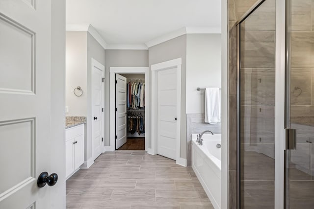 bathroom with a garden tub, vanity, a spacious closet, a stall shower, and crown molding