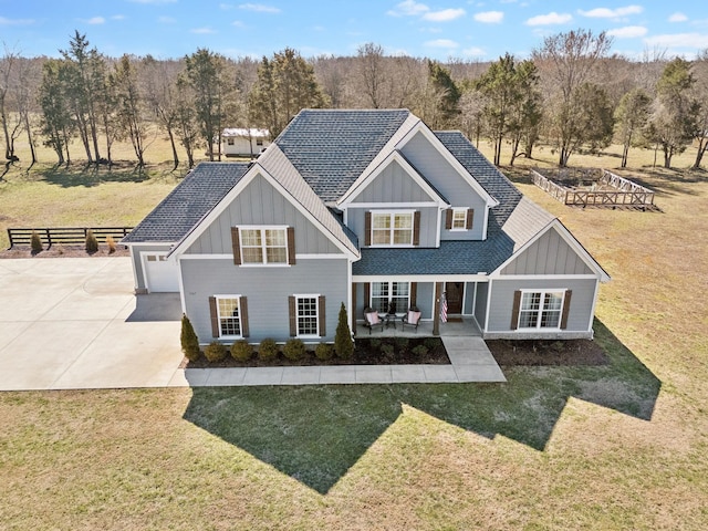 view of front facade with board and batten siding, a front yard, covered porch, and driveway