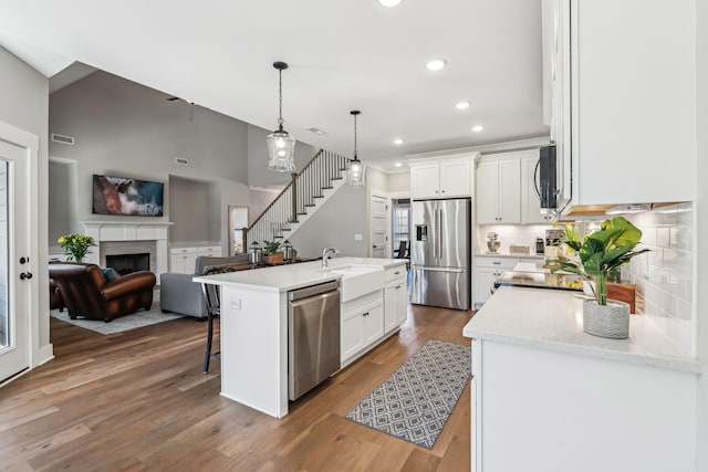 kitchen with a fireplace, appliances with stainless steel finishes, white cabinetry, a sink, and a kitchen bar