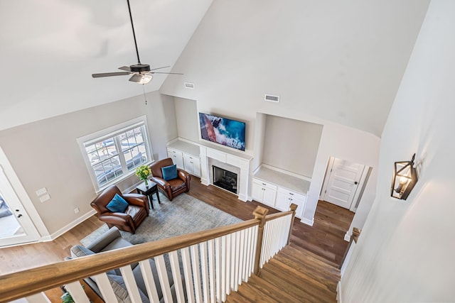 living area with baseboards, visible vents, dark wood finished floors, a fireplace, and high vaulted ceiling