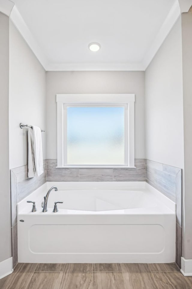 bathroom featuring ornamental molding, wood finished floors, and a bath