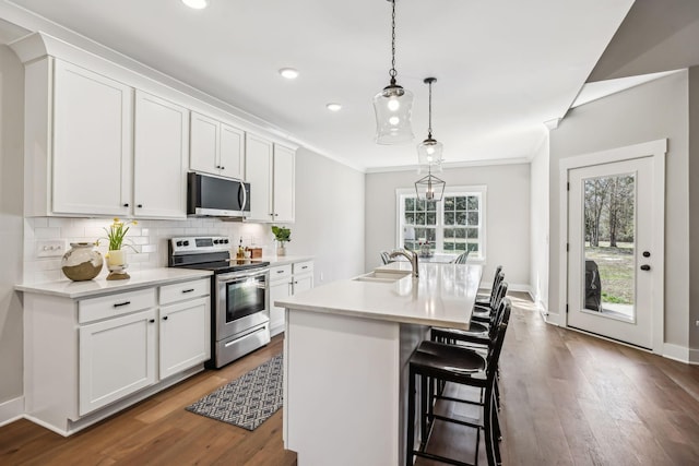 kitchen featuring a sink, stainless steel appliances, crown molding, light countertops, and backsplash