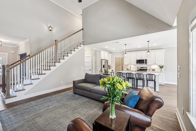 living room featuring light wood-style floors, baseboards, stairway, and ornamental molding