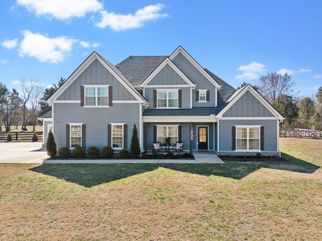 view of front facade featuring a front lawn, board and batten siding, and a shingled roof