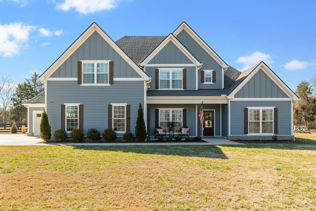 view of front facade featuring roof with shingles, board and batten siding, and a front yard