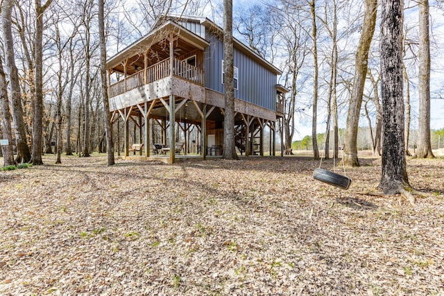 rear view of property featuring board and batten siding, a wooden deck, and stairs