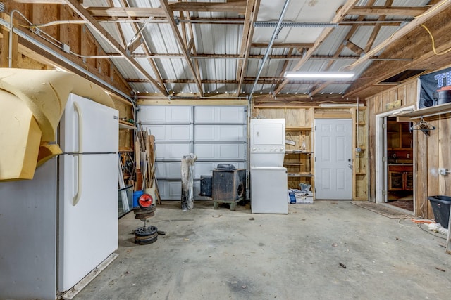 garage with freestanding refrigerator and stacked washing maching and dryer