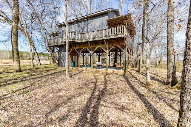 back of property with a carport, board and batten siding, a wooden deck, and driveway