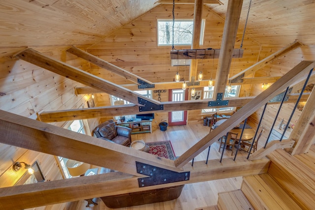 stairs with wood ceiling, wooden walls, high vaulted ceiling, and wood finished floors