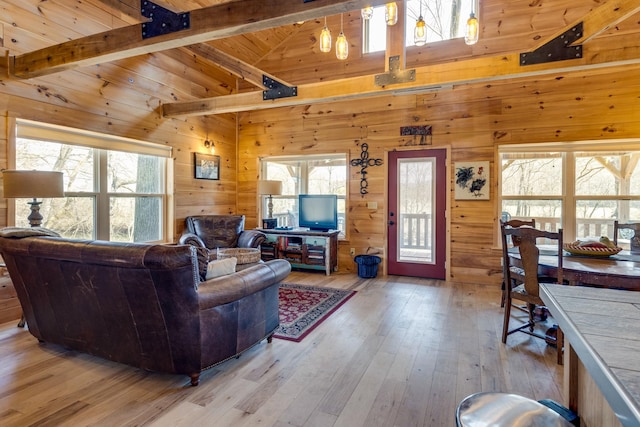 living room featuring high vaulted ceiling, wooden walls, wood ceiling, light wood-type flooring, and beam ceiling