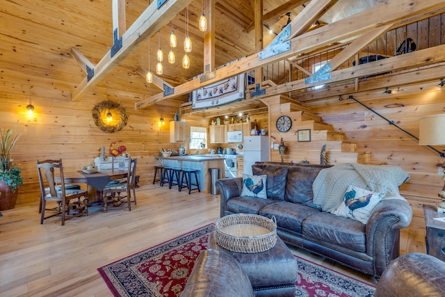 living area featuring wood ceiling, wood walls, high vaulted ceiling, light wood-type flooring, and beamed ceiling