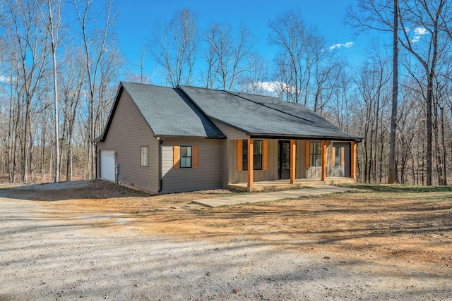 view of front of home featuring covered porch, driveway, a shingled roof, and a garage