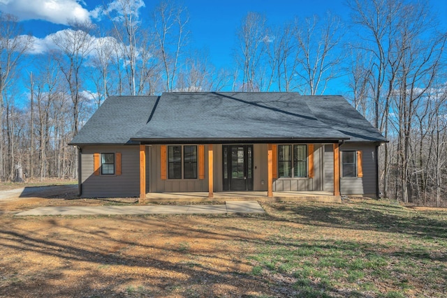 view of front of home with covered porch, a shingled roof, and a front yard