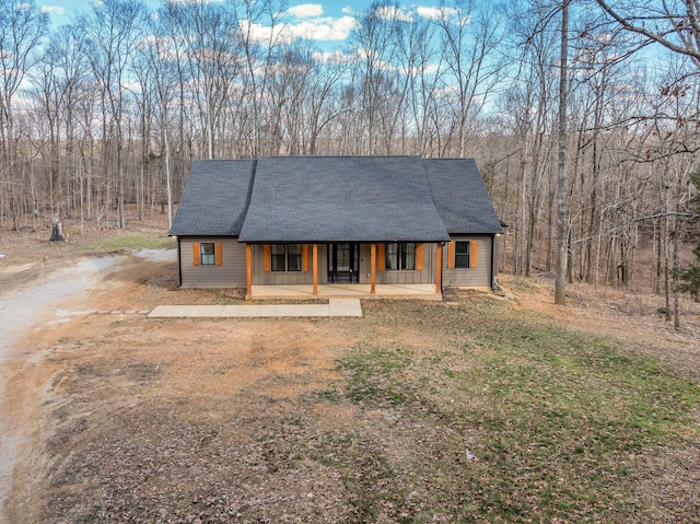 view of front of home with a shingled roof, covered porch, and driveway