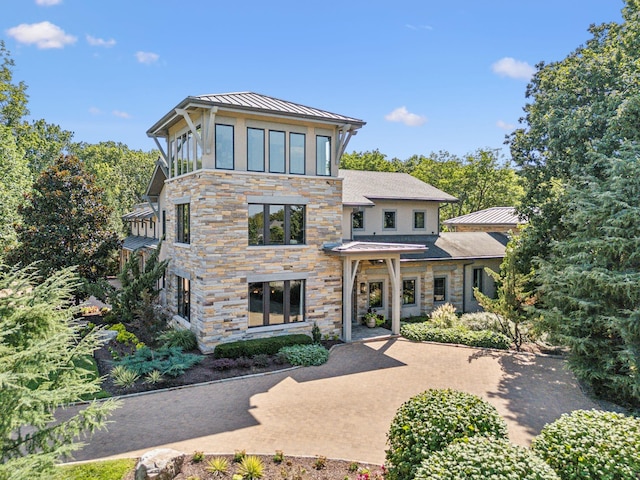 modern home with stone siding, a standing seam roof, and metal roof