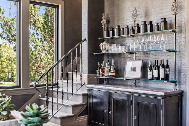 bar featuring stairs, a bar, and a healthy amount of sunlight