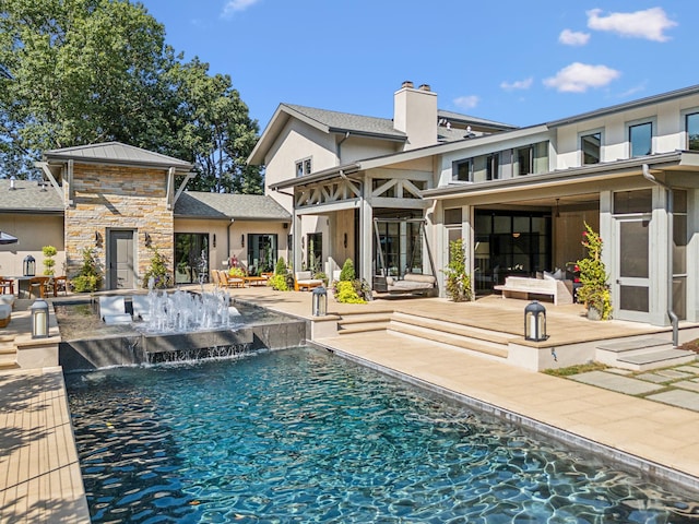 rear view of house featuring a patio area, a chimney, an outdoor pool, and stucco siding