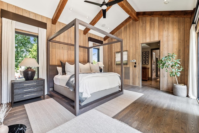 bedroom with high vaulted ceiling, beamed ceiling, wood finished floors, and wooden walls