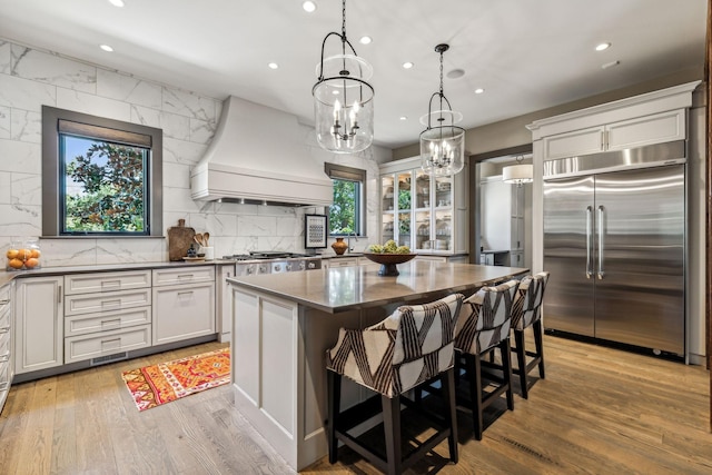 kitchen featuring stainless steel appliances, dark countertops, light wood-style flooring, and custom range hood