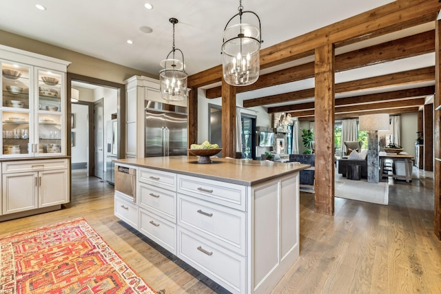 kitchen featuring beamed ceiling, light wood-type flooring, built in fridge, and white cabinetry