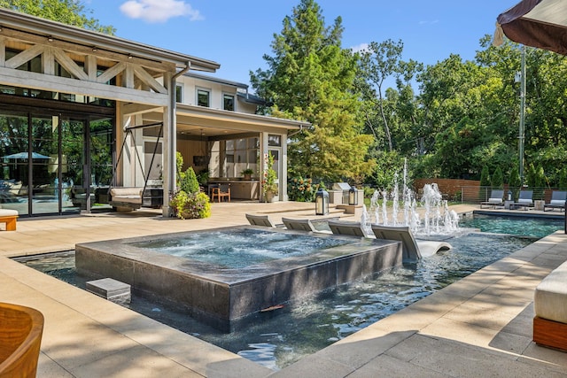 pool with an in ground hot tub, a patio, and fence